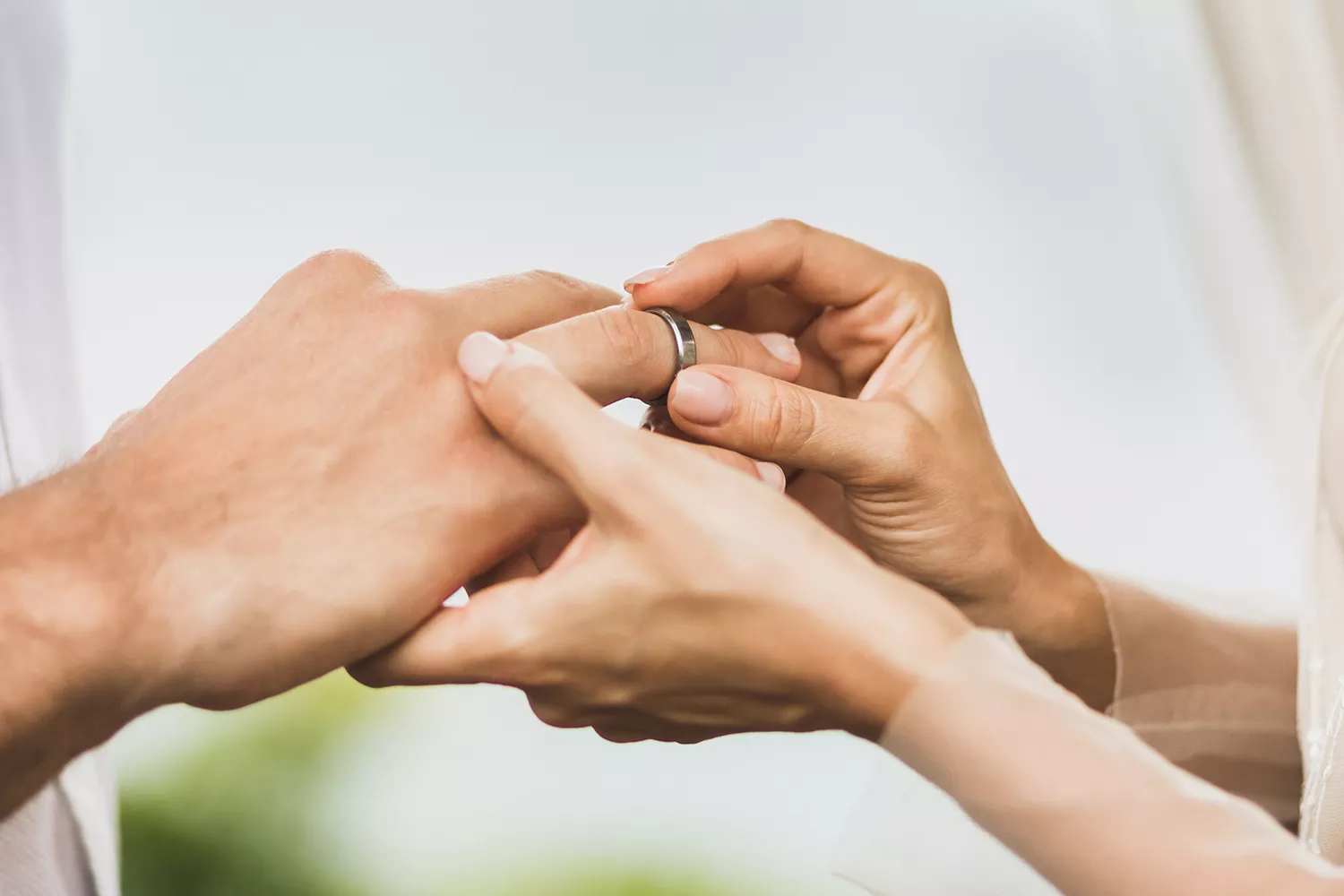 Stock image of bride putting a wedding band on groom's finger